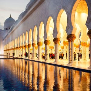 Archs of Shekh Zayed Grand Mosque reflect in the water before it